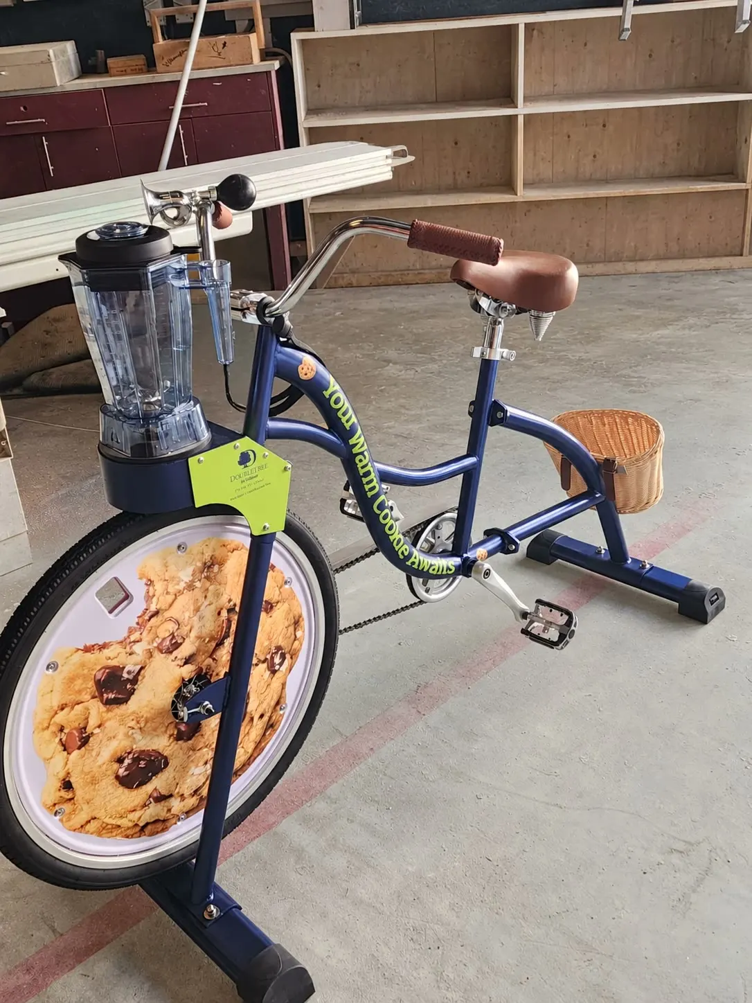 The finished DoubleTree blender bike in the NSQD workshop: navy frame, cookie wheel disc, clear blender jug, lime brand plate